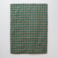 Een productfoto van een deken in groen en beige ontworpen door Kathryn Clark