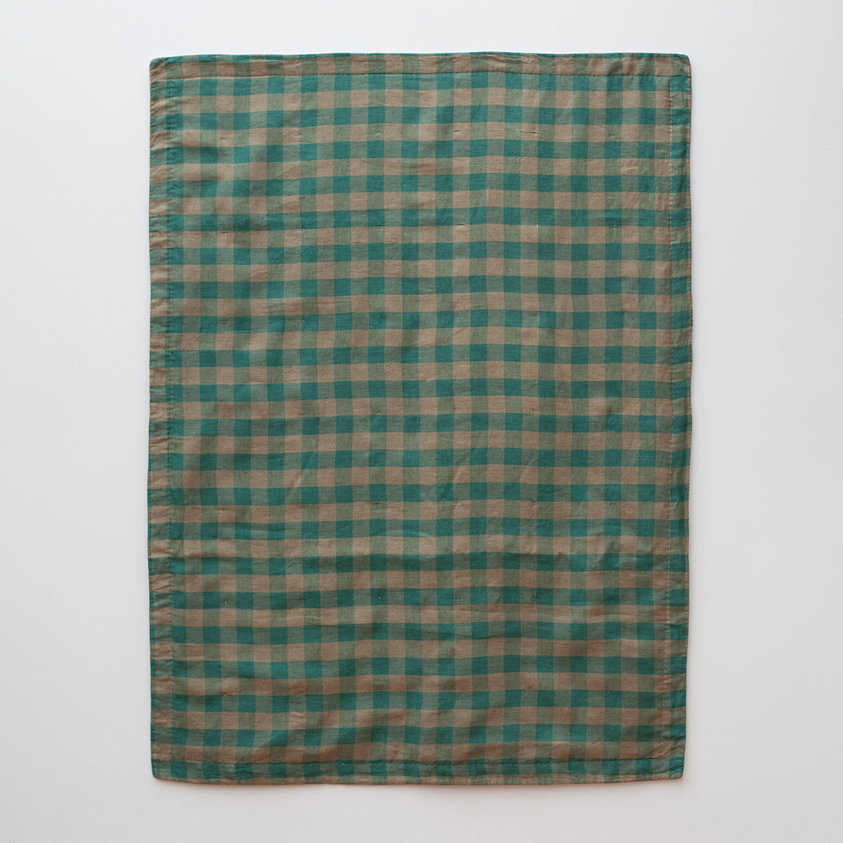 Een productfoto van een deken in groen en beige ontworpen door Kathryn Clark