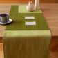 Een overzicht van een mos groene tafelrunner ontworpen door Kathryn Clark gedrapeerd over een houten tafel